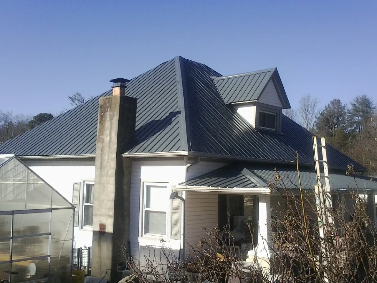 Dark blue standing seam metal roof on a white farmhouse with dormer — Slate & Tile Roof Repair by Roofing Brothers in Kaysville