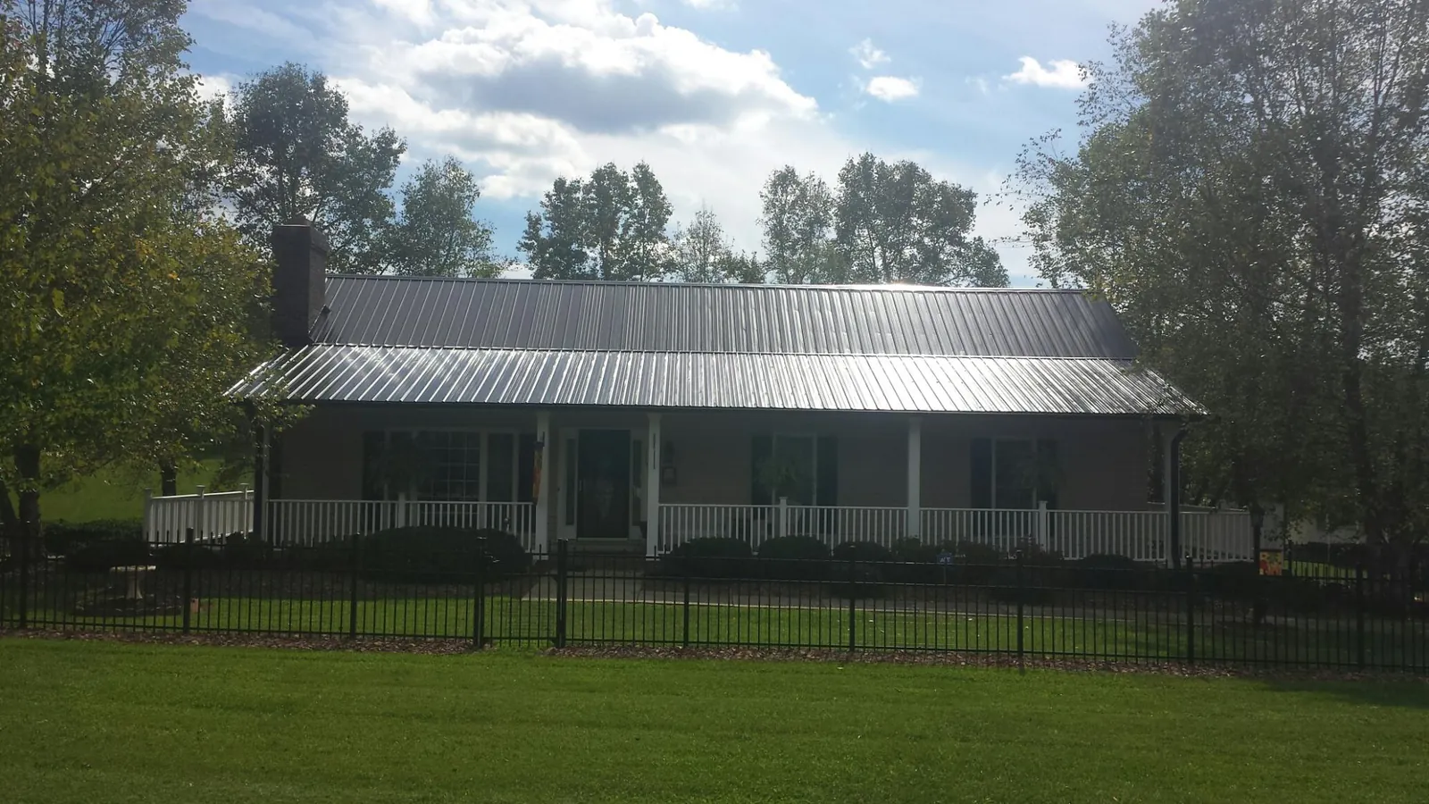 Gray metal roof on a brick ranch with a full width front porch — Gutter Guard Installation work by our crew in Kaysville
