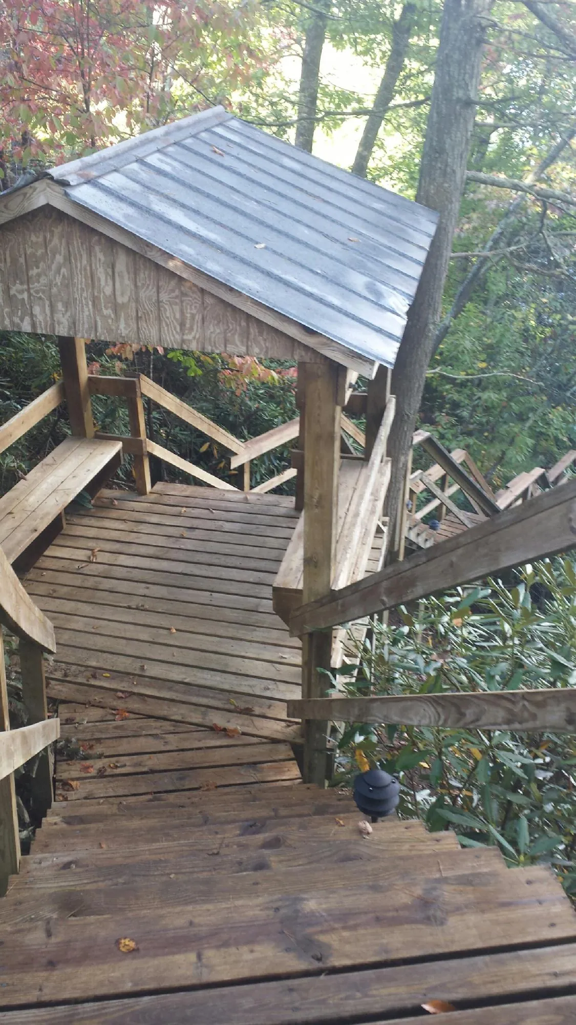 Metal roofed shelter over wooden steps on a wooded walkway — Skylight Repair & Installation work by our crew in Kaysville