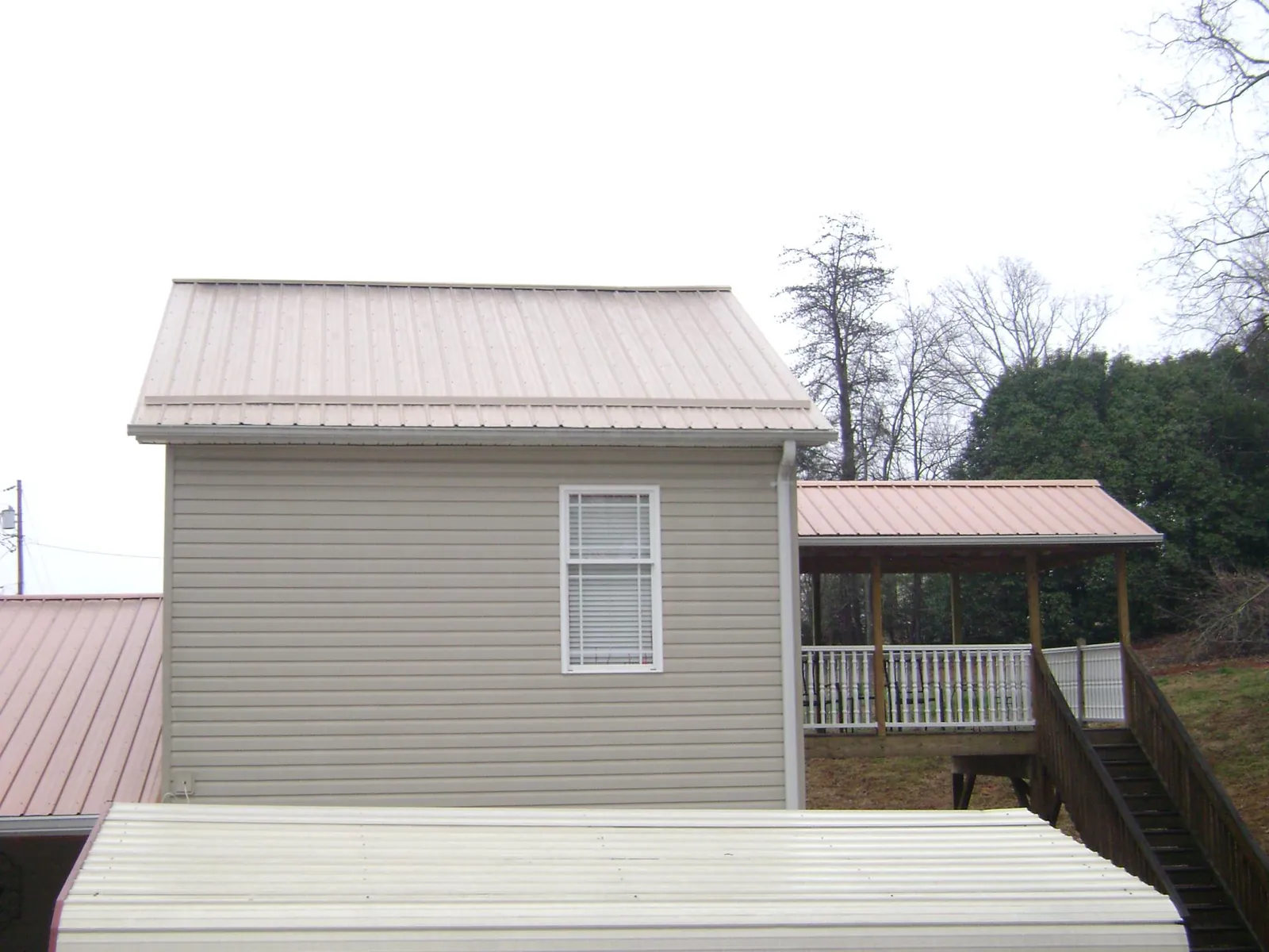 Tan metal roofs on a two story addition and attached porch, from a Roof Replacement job in Kaysville