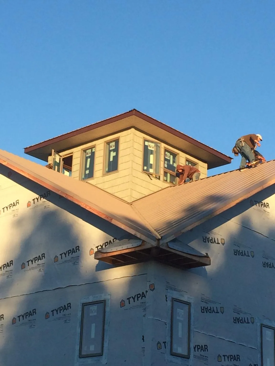 Roofers working around a rooftop cupola on a new metal roof at sunset — Roof Waterproofing in Kaysville by Roofing Brothers